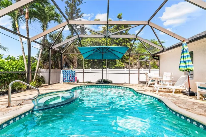 Screened-in swimming pool featuring a curved design and integrated spa