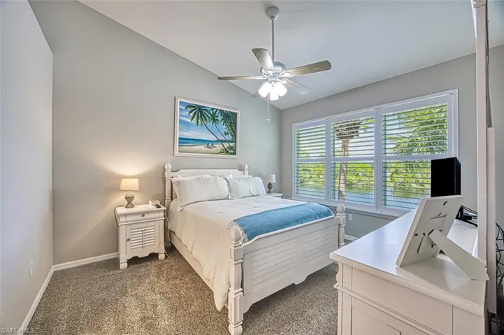 Bedroom with dark carpet, ceiling fan, and lofted ceiling