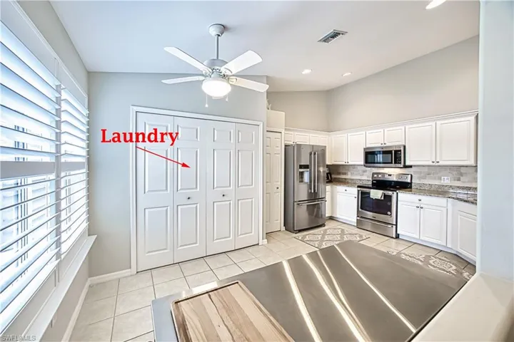 Kitchen featuring ceiling fan, stainless steel appliances, light tile flooring, backsplash, and white cabinets