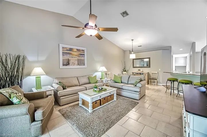 Living room with vaulted ceiling, ceiling fan, and light tile flooring