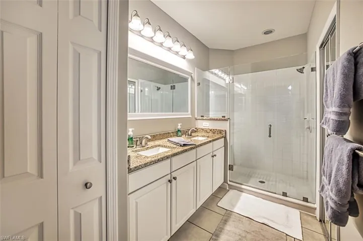 Bathroom featuring dual vanity, tile flooring, and a shower with shower door
