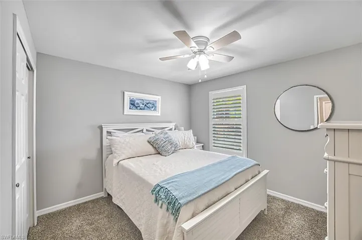 Bedroom with ceiling fan, a closet, and dark colored carpet