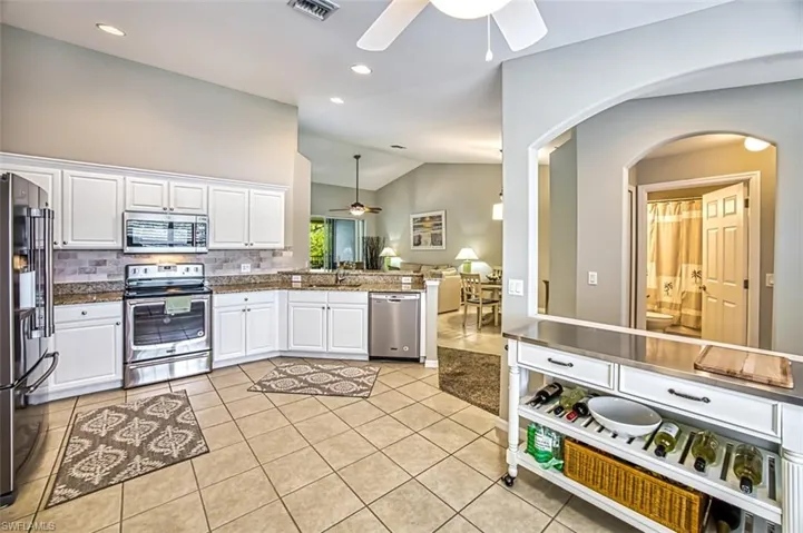 Kitchen with white cabinetry, ceiling fan, light tile floors, and stainless steel appliances