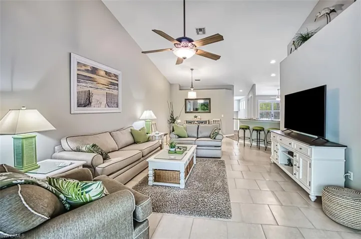 Tiled living room featuring high vaulted ceiling and ceiling fan