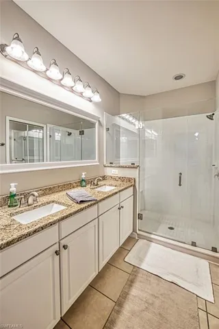 Bathroom featuring tile floors, an enclosed shower, and dual vanity