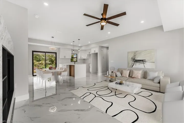 Living area staged featuring recessed lighting, a ceiling fan, light marble finish flooring, and a fireplace