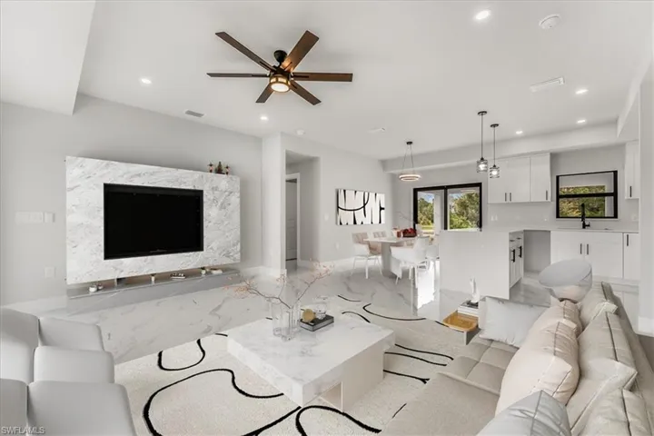 Living area with recessed lighting, light marble finish flooring, and a ceiling fan