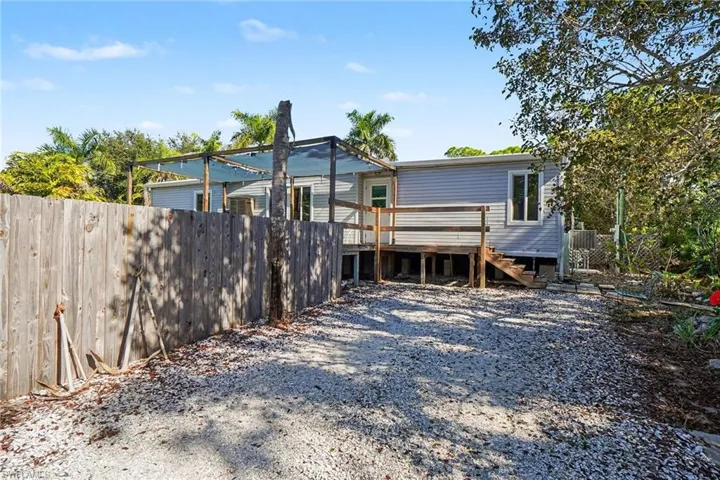 Front view of house with a wooden deck and stairs leading to entry and deck with pool.