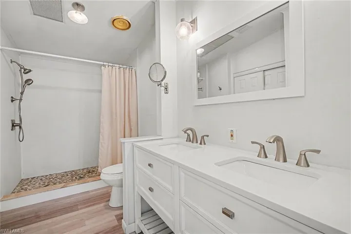 Master Bathroom with a stall shower, light wood finished floors, and double vanity