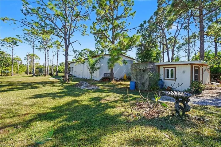 View of green lawn with an outbuilding that has electric and air conditioning.   Large pole building for equipment.