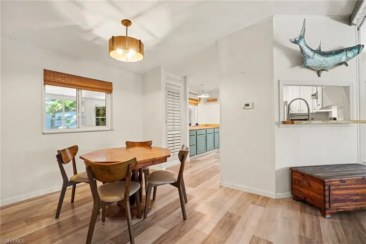 Dining area with light wood-type flooring and view into kitchen
