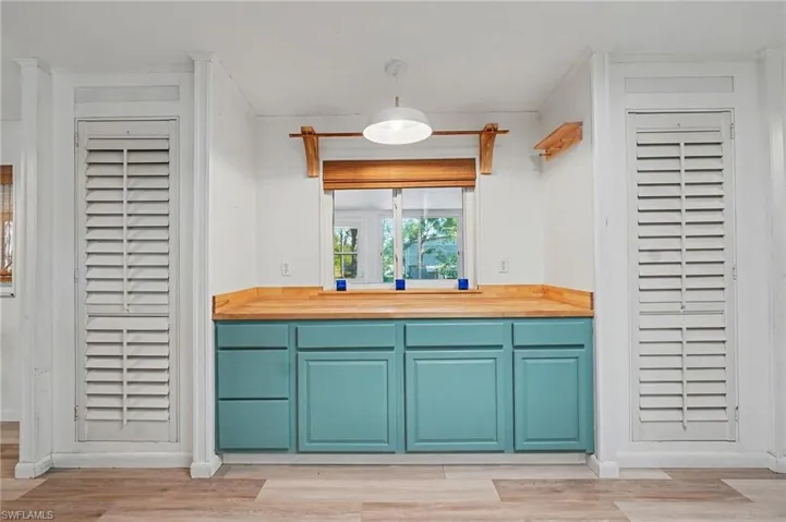 Kitchen with butcher block counters, light wood finished floors, and hanging light fixtures