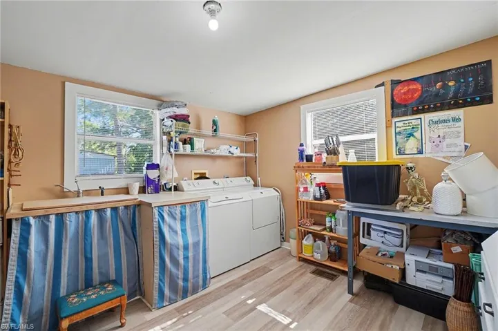 Large laundry room with light wood-type flooring and plenty of natural light. Could be used as office or craft space.