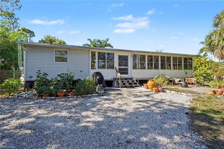 Back of property featuring a sunroom and entry steps.  Great location for grilling and enjoying the fruit trees.