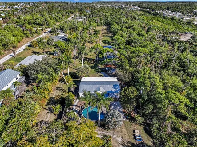 Aerial view of a heavily wooded area.  Property extends to the homes seen in the distance.