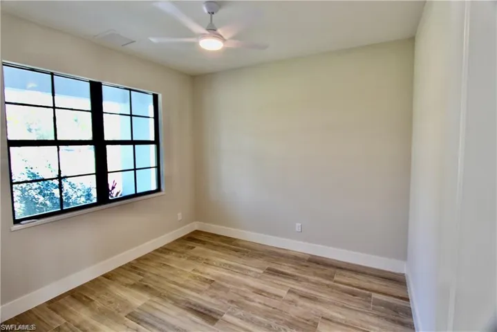 Empty room with ceiling fan, light wood-type flooring, and a wealth of natural light