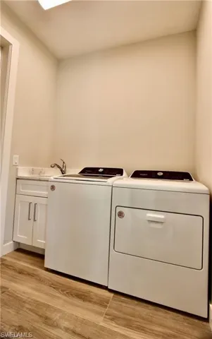 Laundry area featuring cabinets, sink, light hardwood / wood-style flooring, and independent washer and dryer