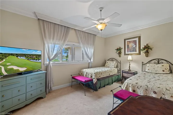 Carpeted bedroom featuring ceiling fan and crown molding
