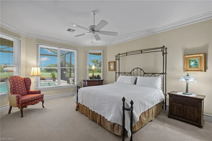 Bedroom with ceiling fan, light colored carpet, and ornamental molding