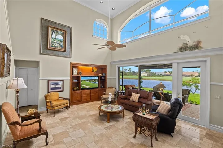 Living room with ornamental molding, a healthy amount of sunlight, a high ceiling, and ceiling fan
