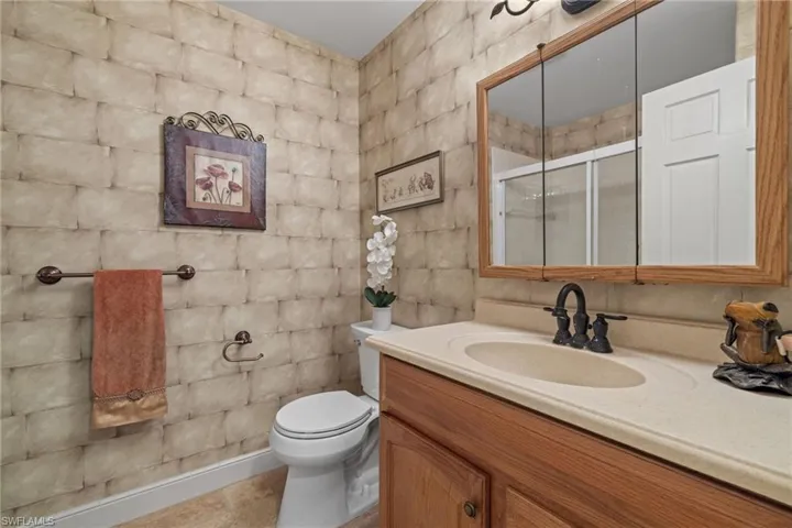 Bathroom featuring tile patterned flooring, walk in shower, toilet, and vanity