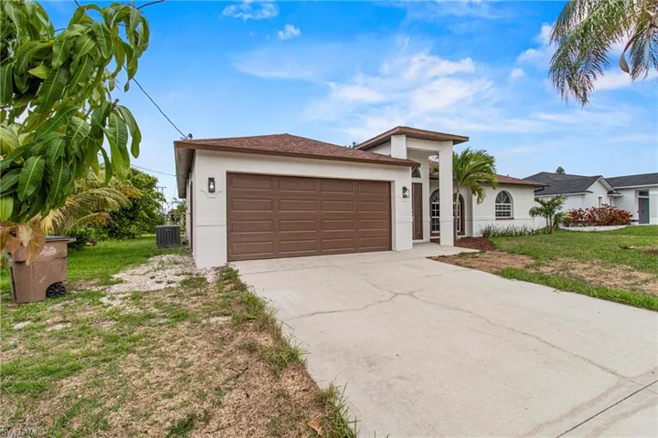 View of front of property featuring a garage, central AC unit, and a front lawn