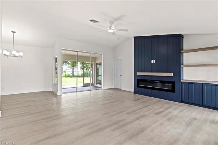 Unfurnished living room with vaulted ceiling, ceiling fan with notable chandelier, light wood-type flooring, and a fireplace