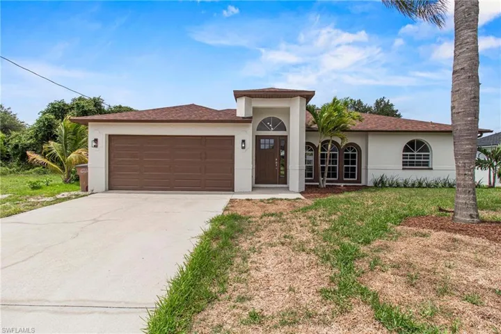 View of front of property featuring a garage and a front lawn