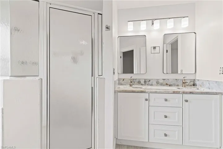 Bathroom featuring double vanity and a shower with shower door