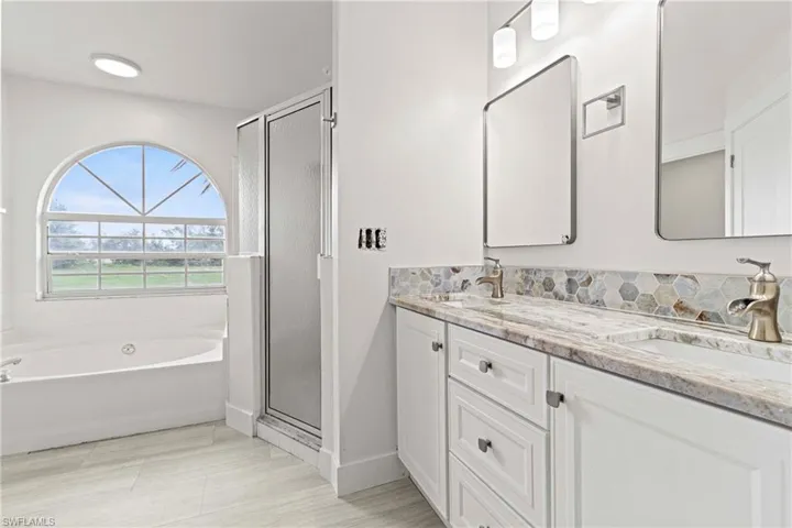 Bathroom featuring dual vanity, tile floors, and independent shower and bath