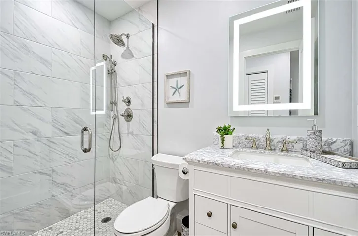 Bathroom featuring a shower with shower door, oversized vanity, and toilet