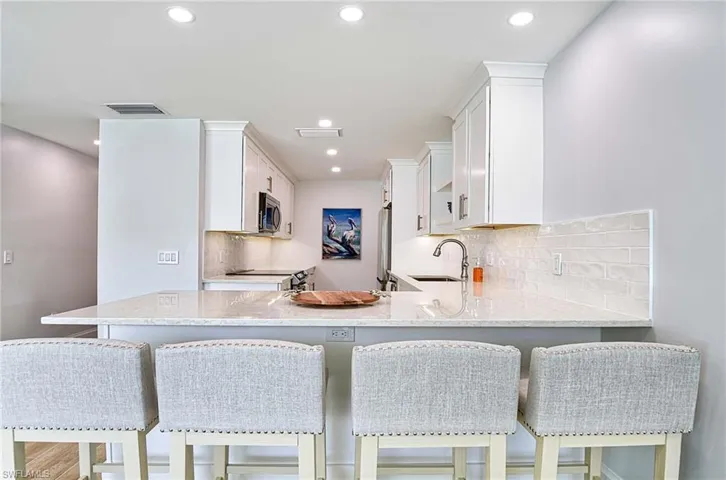Kitchen featuring sink, backsplash, a breakfast bar area, and kitchen peninsula