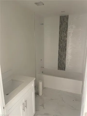 Bathroom featuring vanity, tiled shower / bath combo, and tile patterned floors