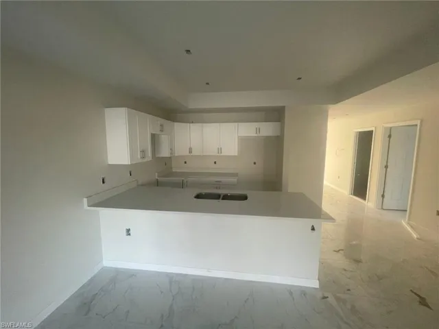 Kitchen with light tile patterned flooring, kitchen peninsula, and white cabinets