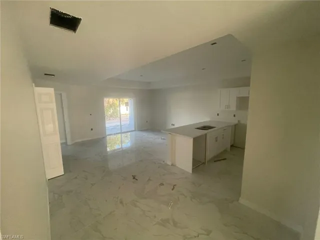 Kitchen with light tile patterned flooring, a kitchen island, and white cabinetry