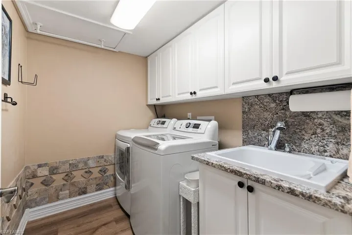 The ample sized laundry room offers cabinets for extra storage and a sink.