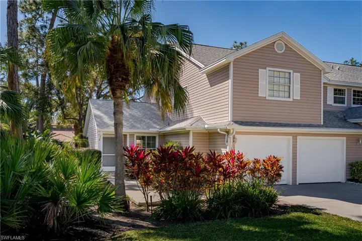 Traditional-style house with a shingled roof, an attached garage, and driveway