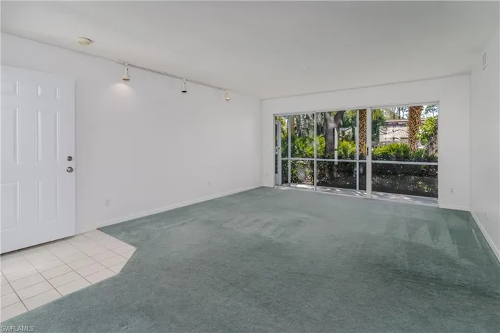 Carpeted empty room featuring track lighting and tile patterned flooring