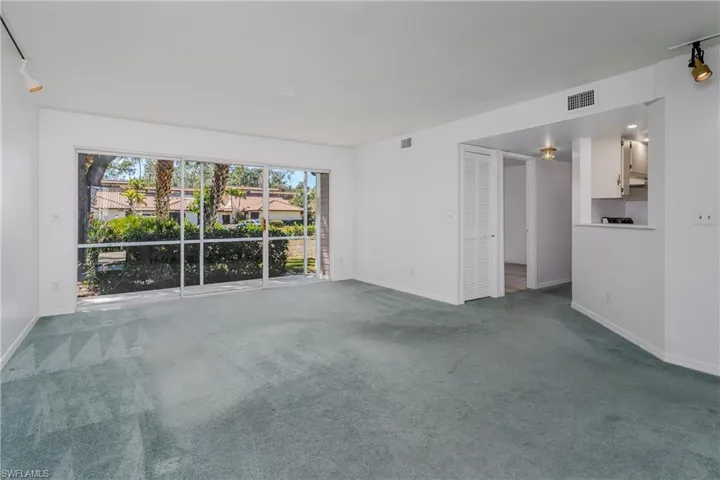 Unfurnished living room featuring track lighting and carpet flooring