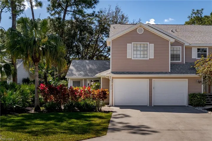 Traditional home featuring a shingled roof, concrete driveway, a front lawn, and an attached garage