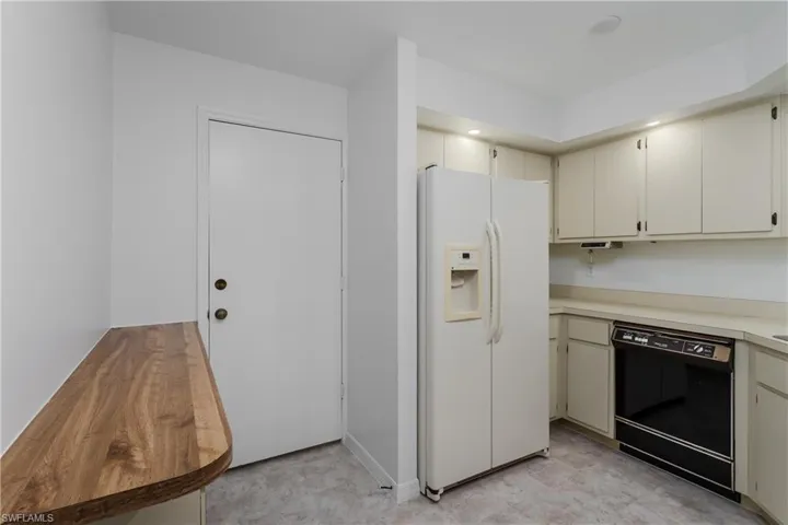 Kitchen featuring white fridge with ice dispenser, dishwasher, light countertops, and light floors