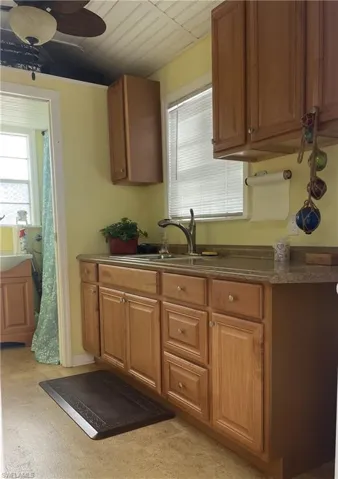 Kitchen featuring wood finish cabinets, dark countertops, and a ceiling fan