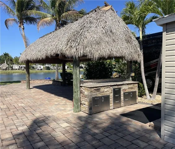 View of patio featuring exterior kitchen, a water view, and a gazebo