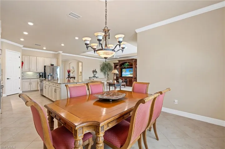 Dining room featuring arched walkways, a notable chandelier, recessed lighting, visible vents, and ornamental molding