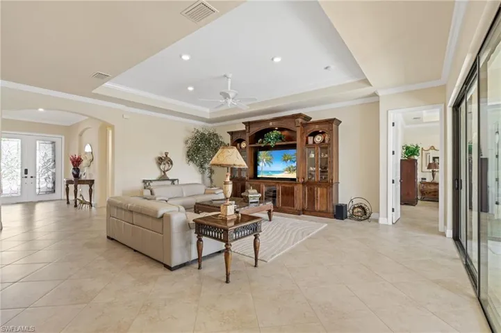 Living area with visible vents, arched walkways, and a raised ceiling