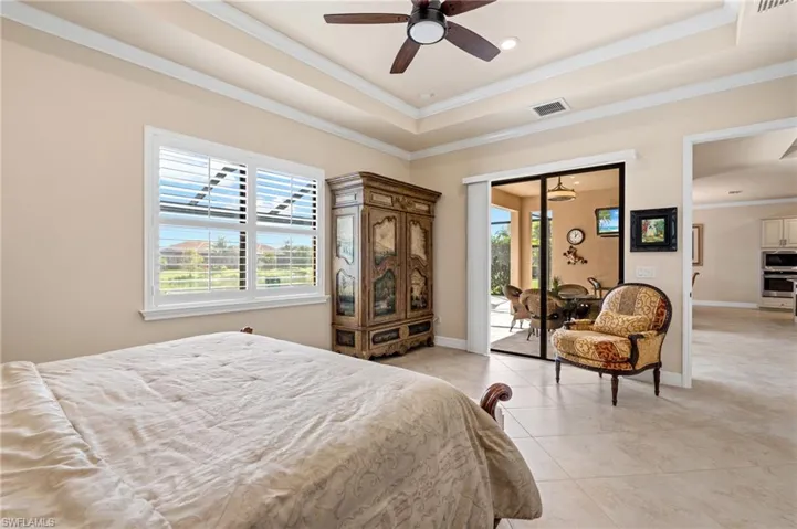 Bedroom featuring a tray ceiling, multiple windows, and visible vents