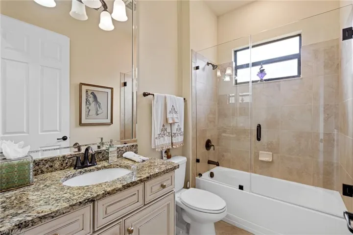 Bathroom featuring combined bath / shower with glass door, vanity, and toilet