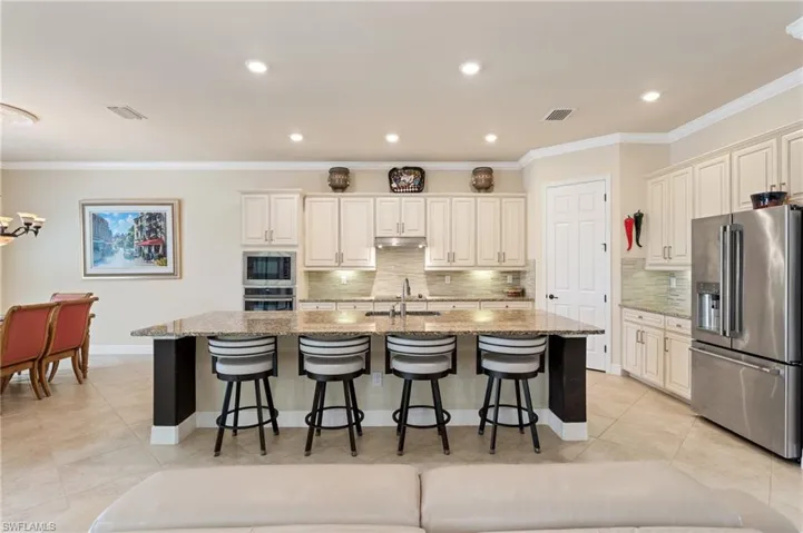 Kitchen with light stone counters, stainless steel appliances, a breakfast bar, a sink, and visible vents