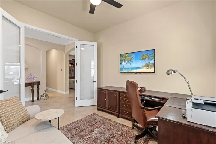 Office area featuring arched walkways, ceiling fan, light tile patterned floors, and baseboards