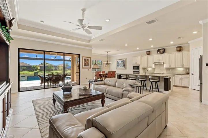 Living room featuring light tile patterned floors, a raised ceiling, and crown molding